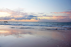 A sandy beach at sunset with waves crashing against the shore at the Sea Oats Estate in Captiva Island, FL