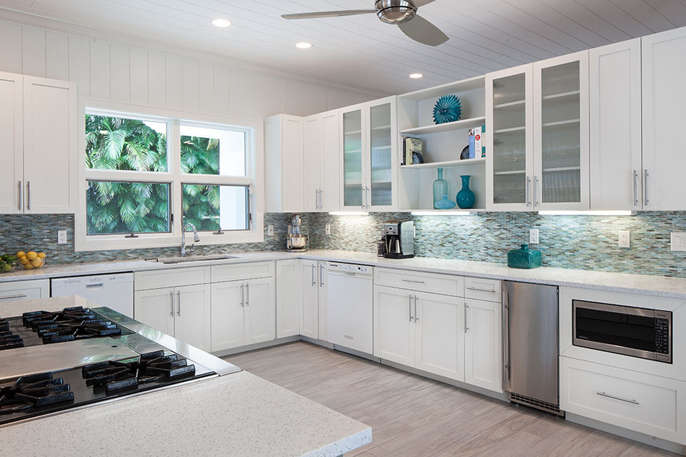 Modern kitchen with white cabinets and white marble with window overlooking trees at the Sea Oats Estate in Captiva Island, FL