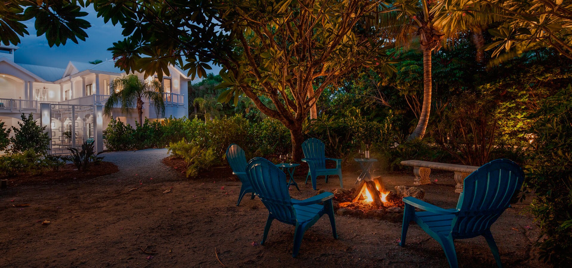 Chairs surrounding outdoor fire near palm trees and sand outside the Sea Oats Estate in Captiva Island, FL