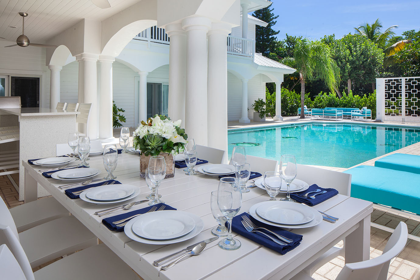 White tables and chairs with dining set and flowers near pool with patio furniture at the Sea Oats Estate in Captiva Island, FL