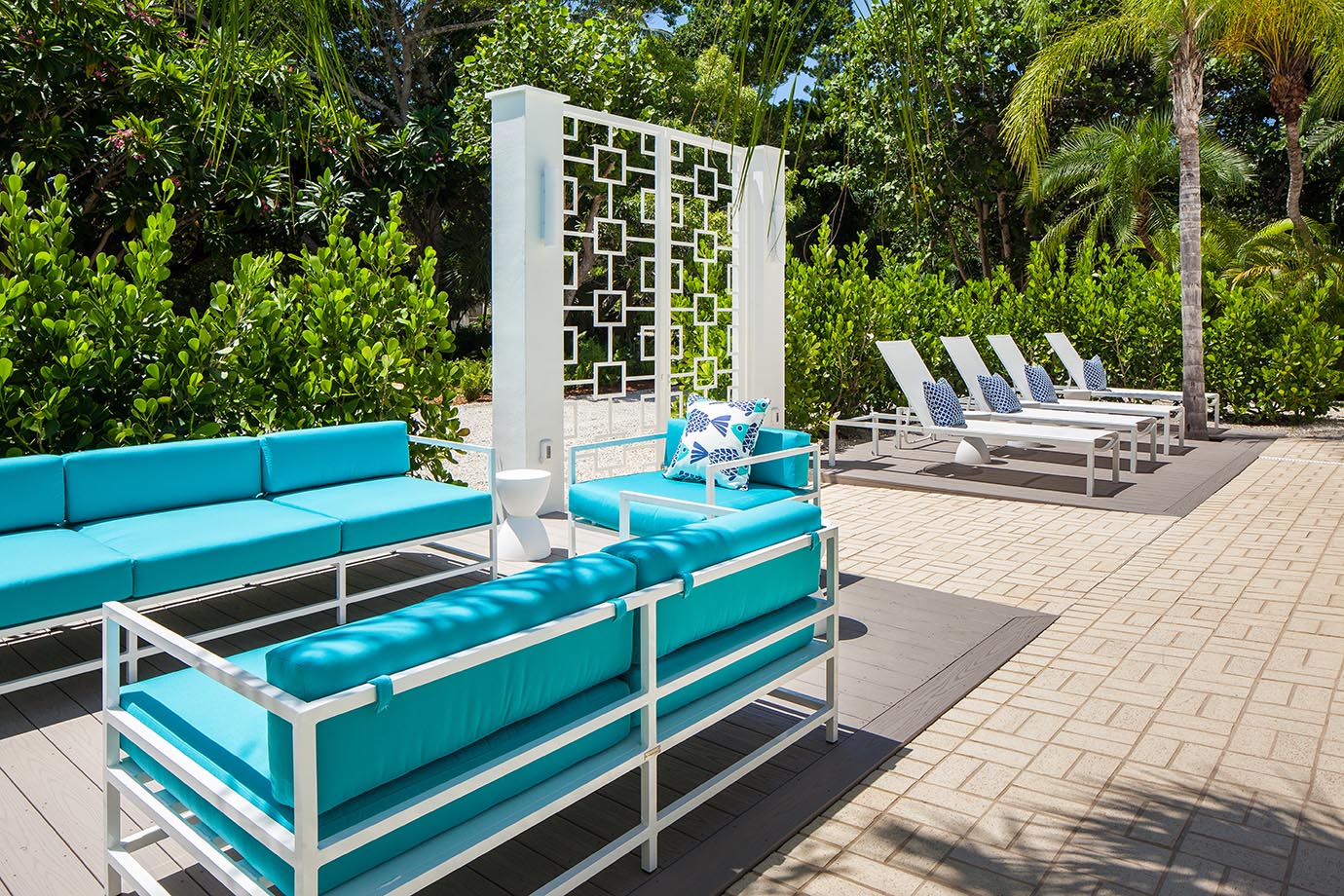 Teal patio furniture next to palm trees near white gate at the Sea Oats Estate in Captiva Island, FL