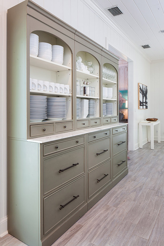 Gray credenza off the kitchen storing white plates and bowls, coffee cups, wine glasses and rocks glasses in Captiva Island, FL estate