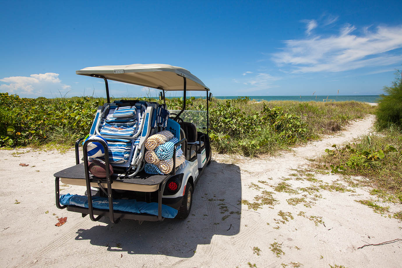 Golf cart on the beach dunes of Captiva Island, FL with beach chairs and towels in tow