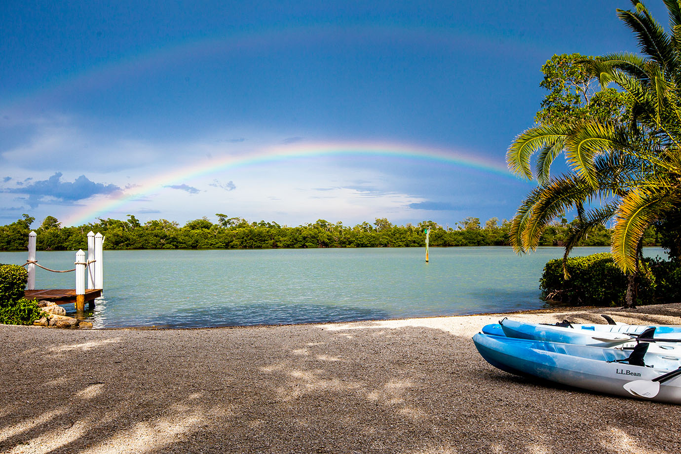 View of the private beach at the Sea Oats Estate with clear blue water and a rainbow over the ocean