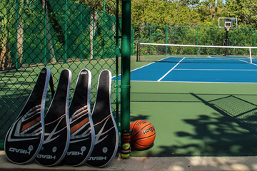 Tennis rackets lined up next to basketball outside outdoor tennis court with basketball hoop at the Sea Oats Estate in Captiva Island, FL
