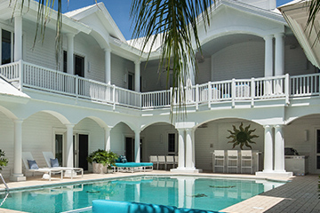 Front view of the the Sea Oats Estate in Captiva Island, FL with pool, poolside chairs and palm trees