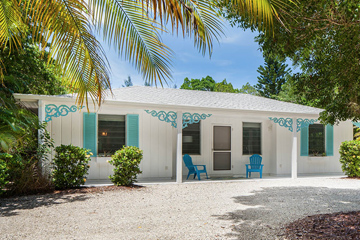 Guest house with blue chairs in front of palm trees and stone driveway at the Sea Oats Estate in Captiva Island, FL