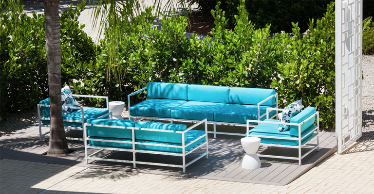 Bright blue and white metal lounge furniture set surrounded by green bushes and palm trees on the patio of the Sea Oats Estate in Captiva Island, FL