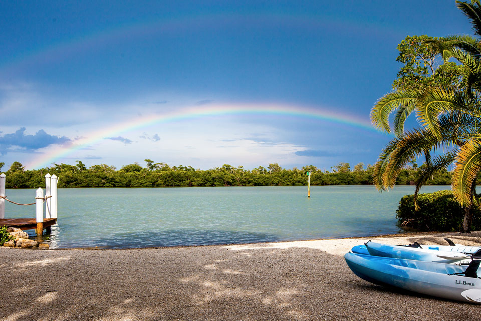 View of the private beach at the Sea Oats Estate with clear blue water and a rainbow over the ocean