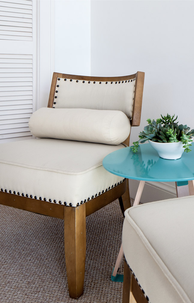 White chair with white pillow near small teal table with a plant on it at the Sea Oats Estate in Captiva Island, FL