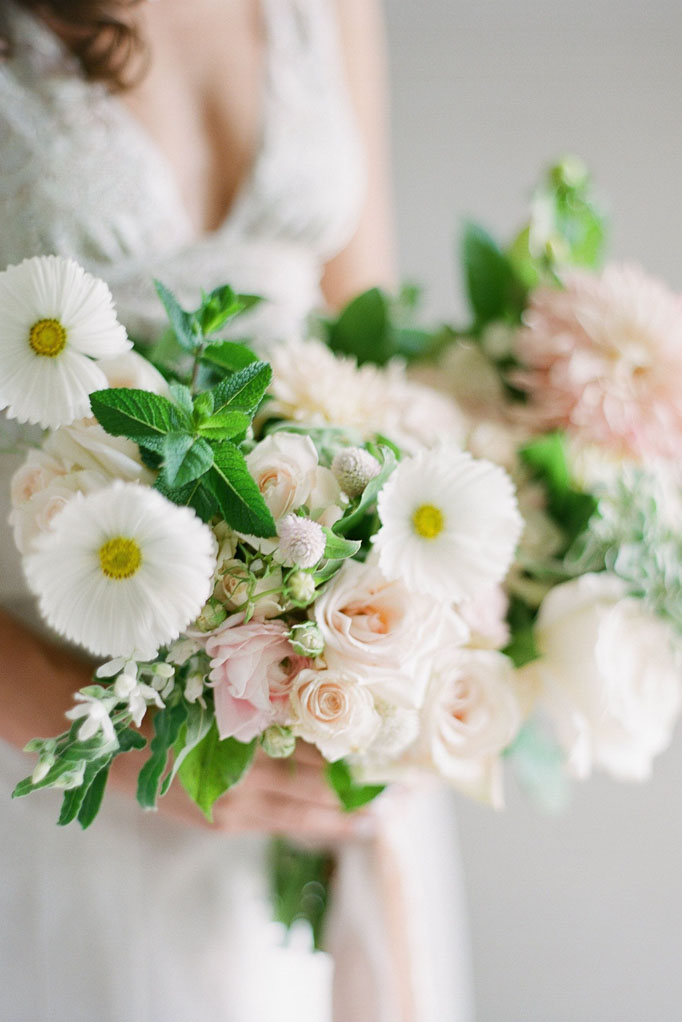 Bride holding her bouquet of white and pale pink florals with greenery at Sea Oats Estate wedding