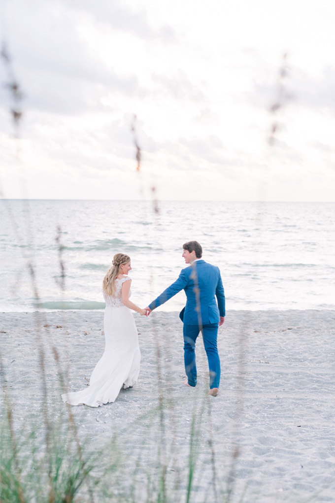 Bride and Groom walking on the beach holding hands after their ceremony at the Sea Oats Estate in Captiva Island, FL