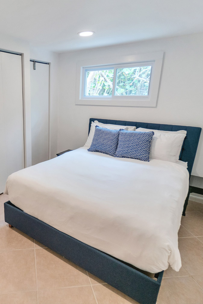 Bedroom in the Captiva Island, FL Sea Oats Estate white a navy blue bed frame with white bedding and pillows, two navy blue and white decorative pillows