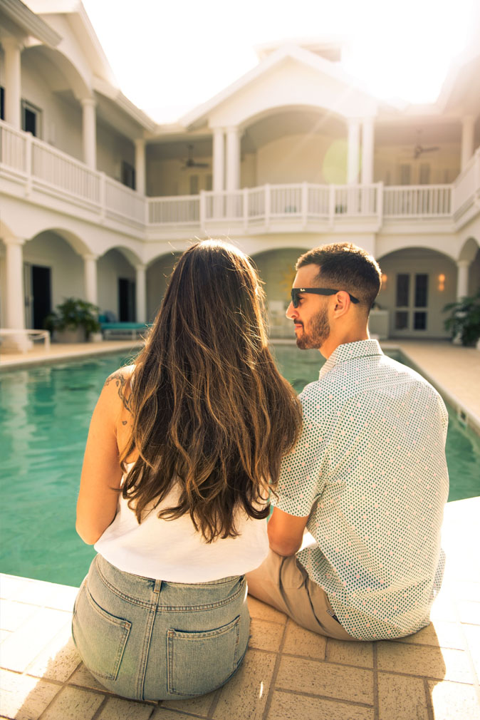 A man and woman sitting by the pool of the the Sea Oats Estate in Captiva Island, FL at dusk