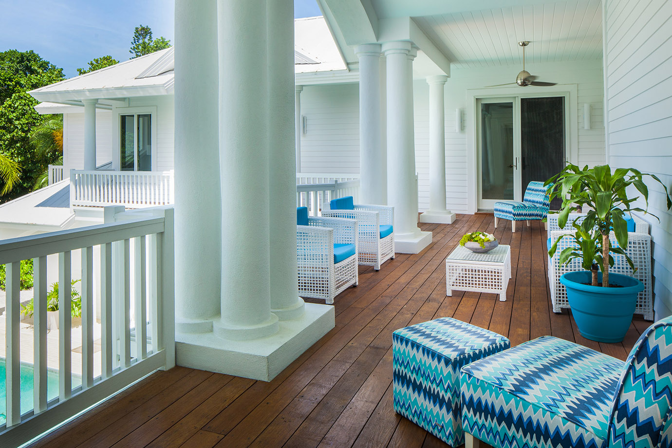 A porch with blue wicker furniture overlooking a pool near a potted plant at the Sea Oats Estate in Captiva Island, FL