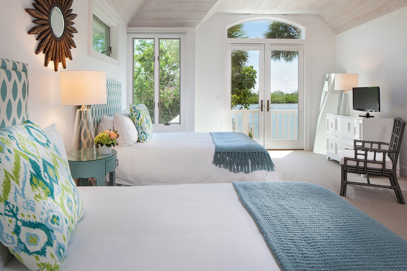 Two Queen Beds with White Linens, Colorful Pillows and Teal Quilts Overlooking Ocean with Private Deck and Television at the Sea Oats Estate in Captiva Island, FL