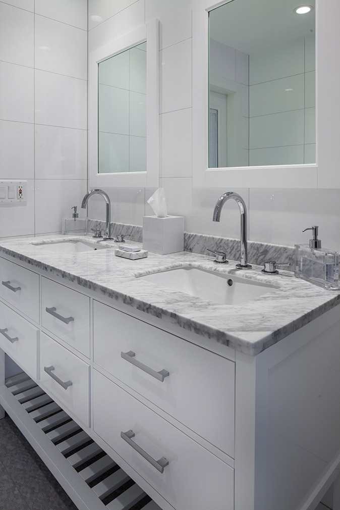 Double wide vanity in the bathroom with grey and white marble countertops with tissues and soap, white cabinets, to large square mirrors at Sea Oats Estate in Captiva Island, FL