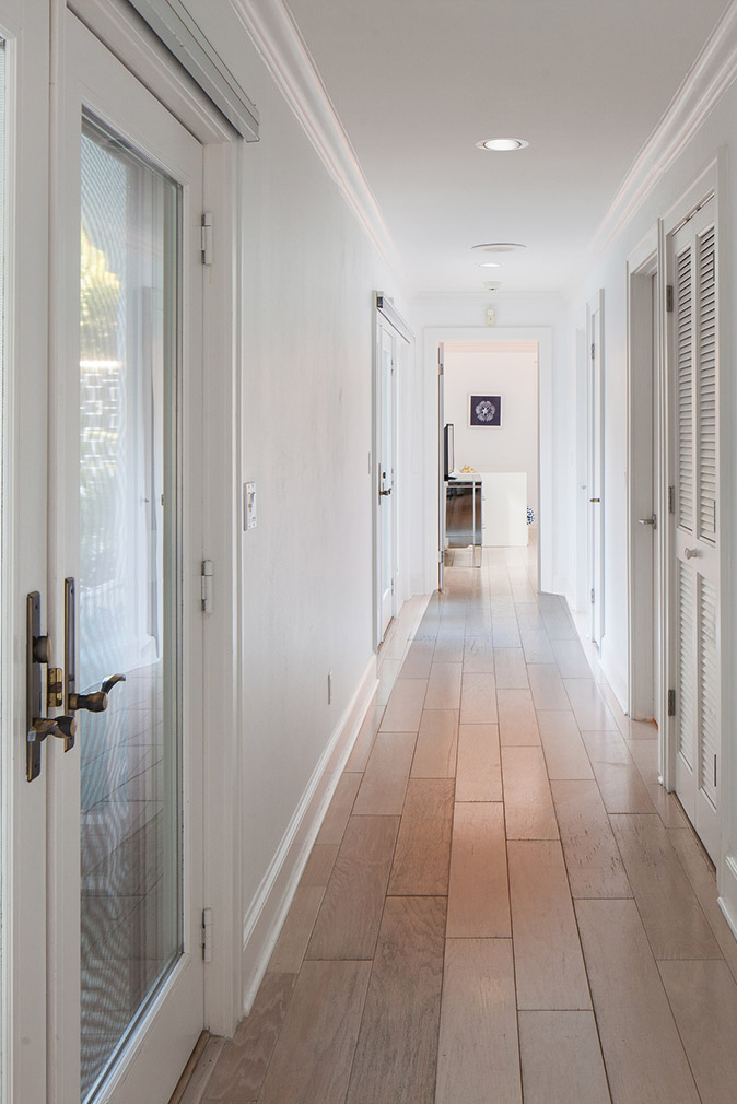 Hallway with white walls and white doors and brown, hardwood floors at the Sea Oats Estate in Captiva Island, FL