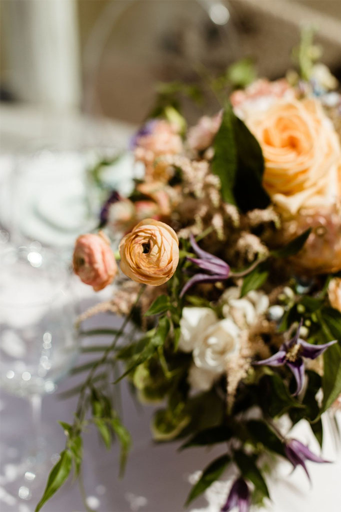 A bouquet of flowers at a wedding reception that are orange, pink and white with purple accents and greenery at Sea Oats Estate